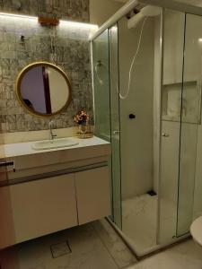 a bathroom with a shower and a sink and a mirror at Apartamento completo no coração de Goiânia in Goiânia