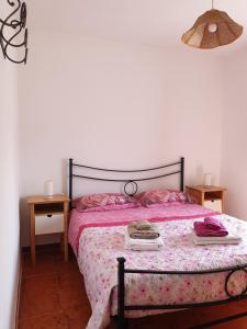a bedroom with a bed with pink sheets and two tables at Villetta Mare Australe in Ardea