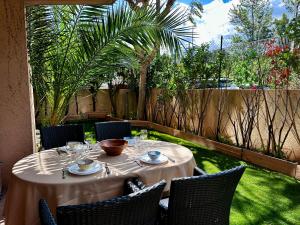 een tafel in een tuin met stoelen en een tafel bij CAP THALASSA - Beau 2P - Piscine - Parking - AC in Roquebrune-Cap-Martin