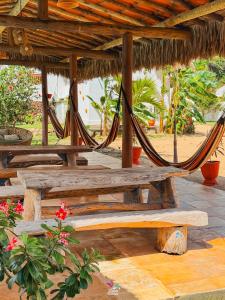 a group of picnic tables with hammocks under a hut at Pousada Curva dos Ventos-Próximo à praia com café da manhã em Icaraí de Amontada in Icaraí +51 photos