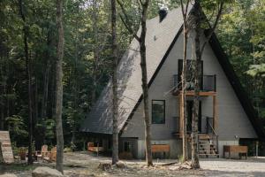 a house with a triangular roof in the woods at Kartalla - the A frame experience in Tremblant in Saint-Rémi-dʼAmherst