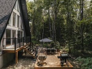 a deck with a table and an umbrella on a house at Kartalla - the A frame experience in Tremblant in Saint-Rémi-dʼAmherst