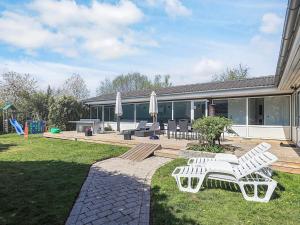 Bøtø Byにある4 star holiday home in Væggerløseの2つの白いベンチと遊び場のある家