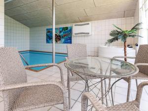 a room with a glass table and chairs and a swimming pool at 14 person holiday home in Væggerløse-By Traum in Marielyst