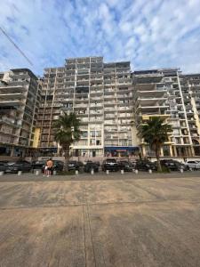 un grand bâtiment avec des palmiers devant dans l'établissement Tiko's Apartments, à Gonio
