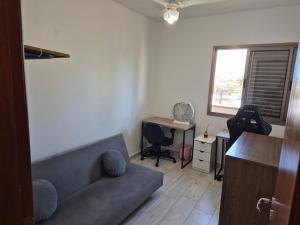 a living room with a couch and a desk at Apartamento Peruíbe in Peruíbe