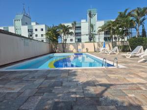 a swimming pool with chairs and a building at Apartamento Peruíbe in Peruíbe +38 photos