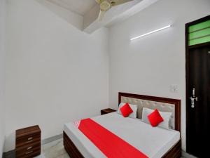a white bedroom with a bed with red pillows at Hotel O Hotel Valentine's in Rohtak