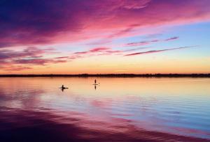 two people are paddle boarding on a lake at sunset at Sunset View in Bongards