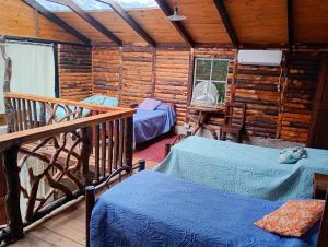 a room with two beds in a wooden cabin at Cabaña Encantada in Vaqueros