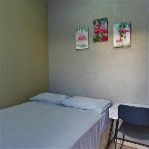 - une chambre avec un lit et trois photos sur le mur dans l'établissement Hostel ElianeMS, à Campo Grande