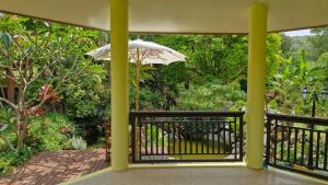 a balcony with an umbrella and a garden at Nature's Hideaway Homestay in Ban Lam Thong Lang