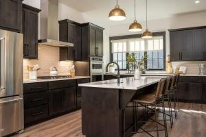 a kitchen with black cabinets and a large island with bar chairs at Rocky Mountain Retreat in Winter Park