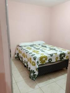 a bed in a room with a floral blanket on it at Casa Aconchegante de 2 quartos e 2 cama de casal e 1 de solteir in Juazeiro do Norte