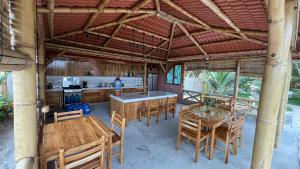 a kitchen and dining room with wooden tables and chairs at Sirena's Beach & Surf Club in Canoa