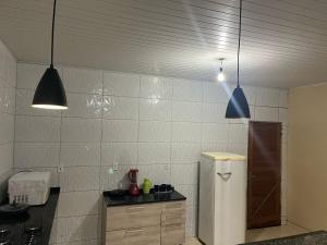 a kitchen with two pendant lights and a refrigerator at Casa Ampla com 5 camas e 2 quartos in Juazeiro do Norte
