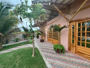 a house with a palm tree and a walkway at Sirena's Beach & Surf Club in Canoa