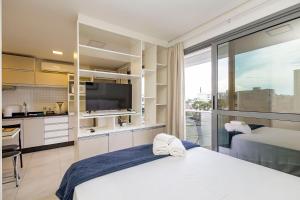 a bedroom with a white bed and a large window at Lindo apto com garagem! in Curitiba