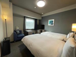 a hotel room with two beds and a chair at Hotel Route Inn Okayama Ibara in Ibara +47 photos