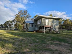 a house on a grassy field with a fence at Scenic Rim Farmstead Retreat in Rathdowney