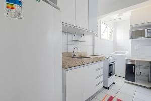 a white kitchen with a sink and a stove at 4let Verano Ponta Negra in Natal