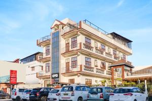 a building with cars parked in front of it at Hotel O The Gomti Hotel in Dehradun