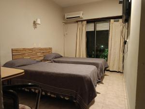 a room with two beds and a window and a table at Hotel Manzanares Plaza in Buenos Aires