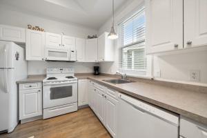 a white kitchen with white cabinets and a sink at The Elm - 36 Hollow in Cherry Valley