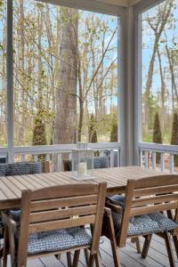 a wooden table and chairs on a porch with a large window at The Elm - 36 Hollow in Cherry Valley