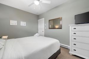 a white bedroom with a bed and a flat screen tv at The Snowberry - 67 Butternut in Cherry Valley