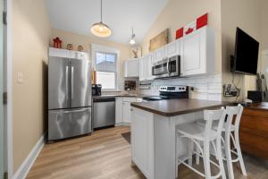 a kitchen with white cabinets and a stainless steel refrigerator at Le Wapiti - 75 Butternut in Cherry Valley
