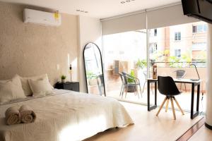 麦德林New Apt w private Jacuzzi & AC的一间卧室配有一张床铺和一张桌子,并设有一个阳台