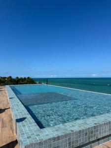 a swimming pool with the ocean in the background at Tamandaré Refúgio Luxuoso com Piscina Infinita e Mar Azul in Tamandaré