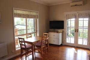 a dining room with a table and chairs and a television at Bryn Glas Farm Stay in Moruya
