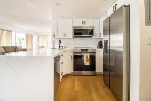 a kitchen with white cabinets and a stainless steel refrigerator at City and Palm View Oceanfront Bliss with Free Parking in Honolulu