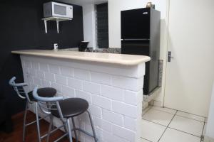 a kitchen with a counter with two stools and a refrigerator at Super Suite con baño y cocina excelente ubicación in Mexico City