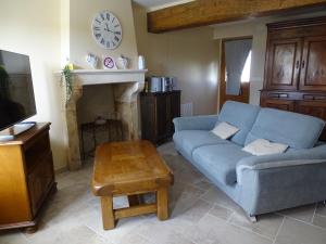 un soggiorno con divano blu e orologio sul muro di Charmant Gîte en Brenne avec Jardin, Piscine Partagée et Proximité Sentiers de Randonnée - FR-1-591-99 a Prissac