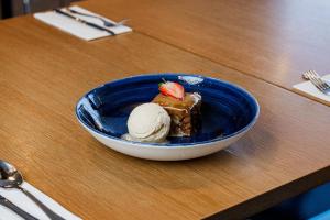 a blue bowl with a piece of cake and ice cream at Holiday Inn Express Aberdeen Airport by IHG in Dyce