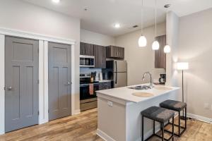 a kitchen with a sink and a counter with stools at CozySuites - Penrose On Mass with pool and parking#10 in Indianapolis +14 photos