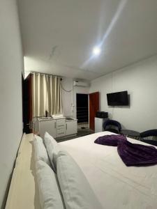 a bedroom with a large white bed and a television at Colony Stay in Paramaribo