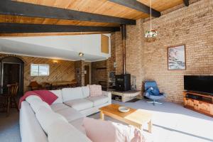 ジンダバインにあるAviemore - 2 14 Cobbodah Streetの白いソファとレンガの壁が備わるリビングルーム