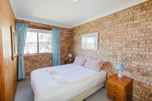 ジンダバインにあるAviemore - 2 14 Cobbodah Streetのベッドとレンガの壁がある寝室