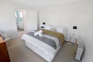 a white bedroom with a bed and a mirror at Mackenzie Batch in Twizel