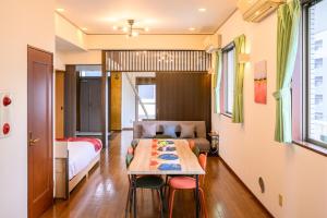 広島市にあるCOCOSTAY 中広ネオイズム 最大10人 閑静な住宅街にある贅沢80m2の最上階プライベートオーナーズルームのベッド、テーブル、椅子が備わる客室です。