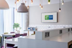 a room with tables and chairs and a tv on the wall at Holiday Inn Express Aberdeen Airport by IHG in Dyce