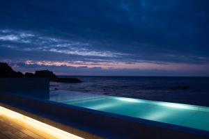 a swimming pool in front of the ocean at night at Lapita Resort in Sakai