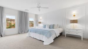 a white bedroom with a bed and a window at The Homestead At The Farmhouse in Pokolbin