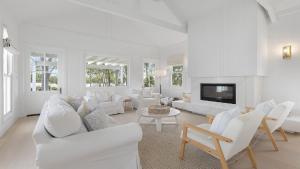 a living room with white furniture and a fireplace at The Homestead At The Farmhouse in Pokolbin