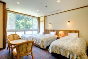 a hotel room with two beds and a window at Yugawara-Onsen Manyoso in Yugawara