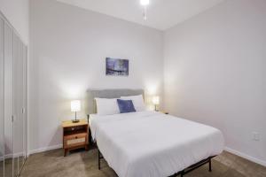 a bedroom with a large white bed and a nightstand with a bed sidx sidx at CozySuites Sky Central #3 in Cincinnati